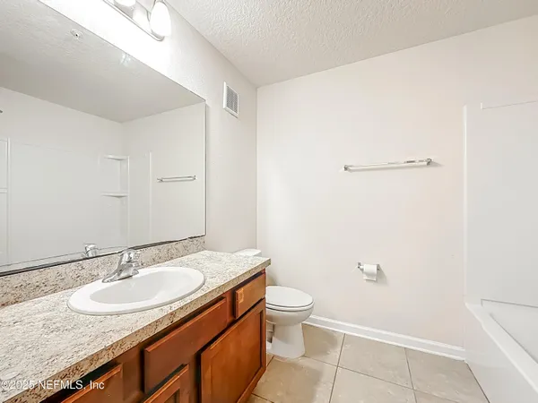 a bathroom with a granite countertop sink a toilet and a mirror