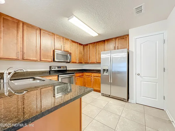 a kitchen with granite countertop a refrigerator sink and cabinets