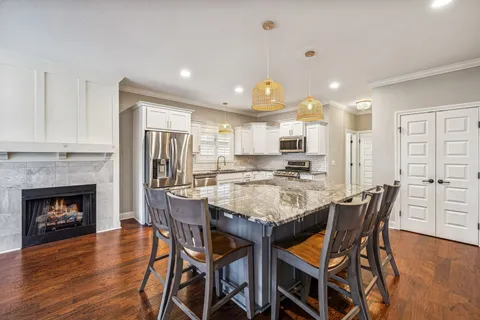 a kitchen with stainless steel appliances granite countertop a stove top oven a sink dishwasher a refrigerator and cabinets with wooden floor