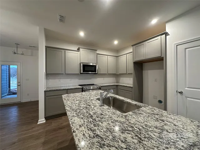 a kitchen with stainless steel appliances granite countertop a refrigerator a sink a stove and cabinets