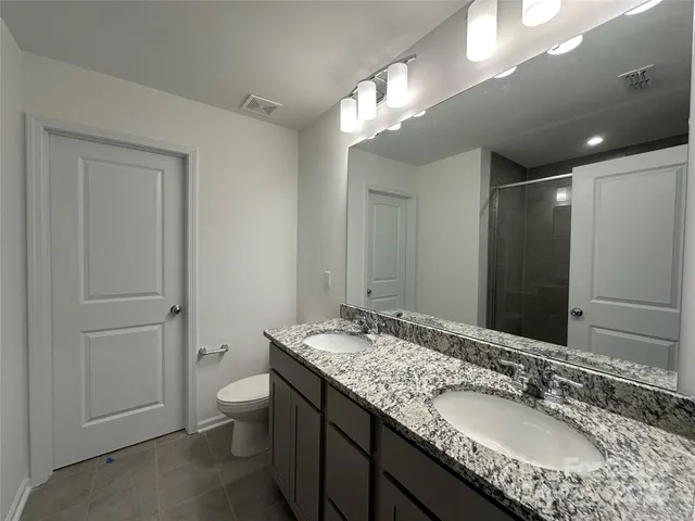a bathroom with a granite countertop sink a toilet and a large mirror