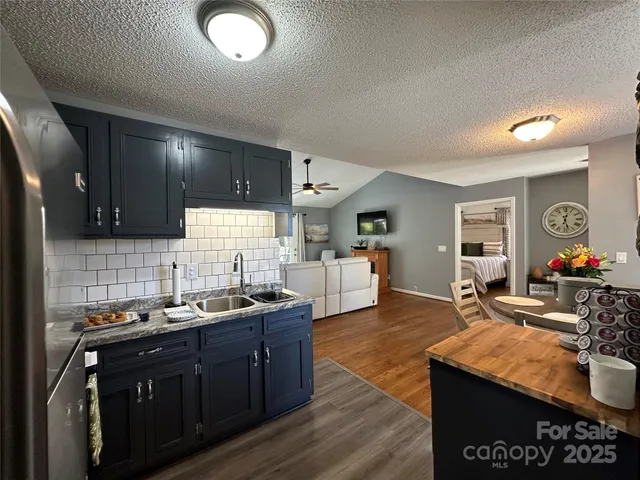 a living room with furniture a wooden floor and a kitchen