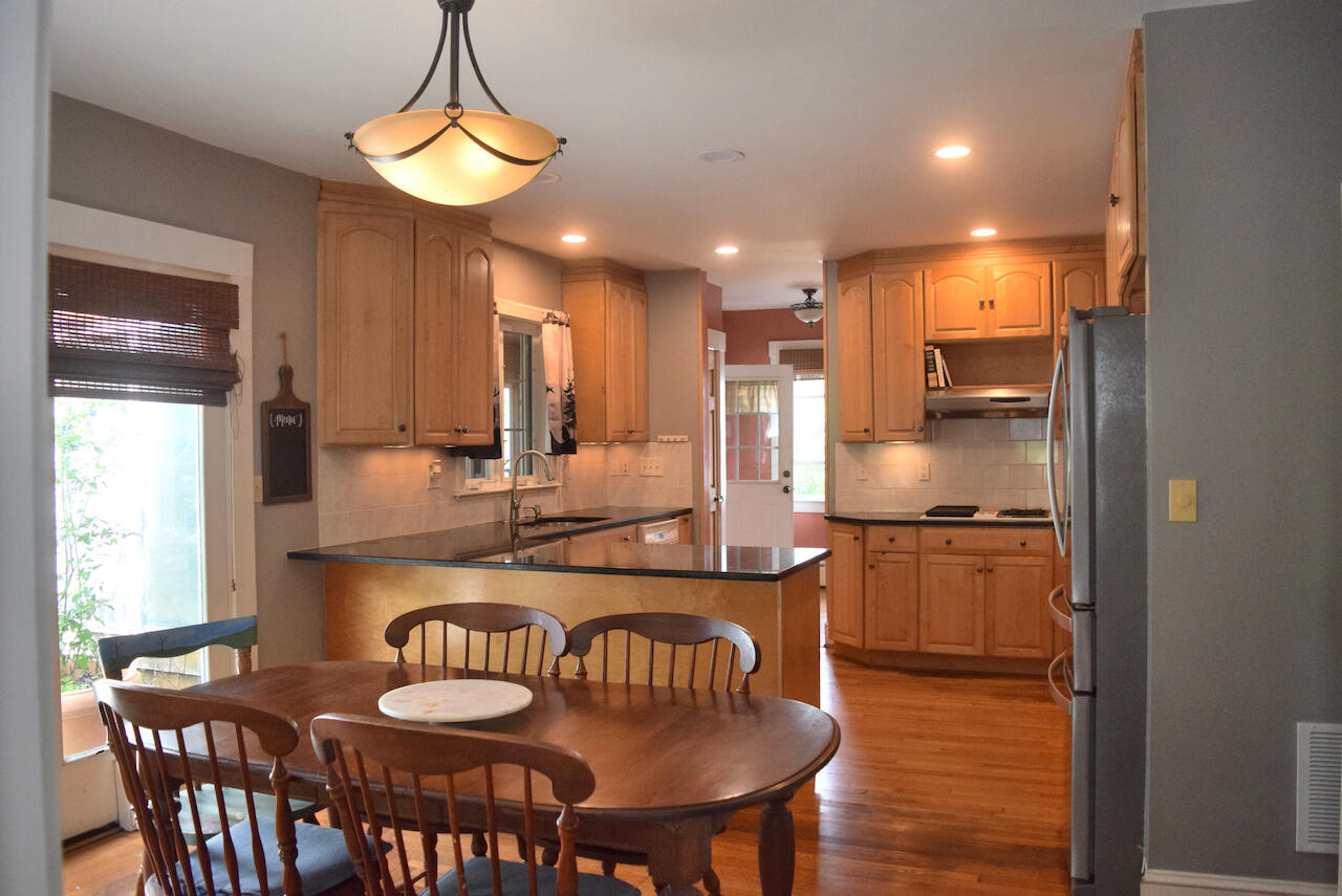99 South Main Street Acushnet, MA 02743 - Photo 11 of 46 a kitchen with stainless steel appliances granite countertop a stove a refrigerator a kitchen island a dining table and chairs with wooden floor