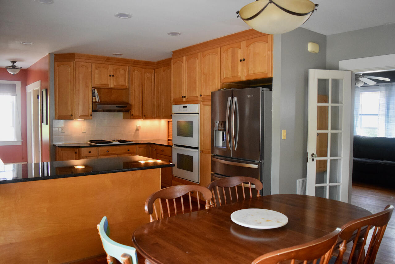 99 South Main Street Acushnet, MA 02743 - Photo 12 of 46 a kitchen with stainless steel appliances granite countertop a stove a refrigerator a kitchen island a dining table and chairs with wooden floor