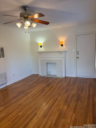 a view of empty room with wooden floor and fan