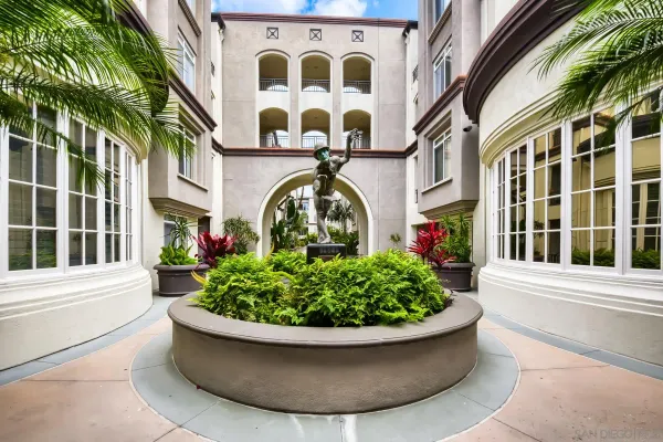 a view of tall house with a fountain and potted plants