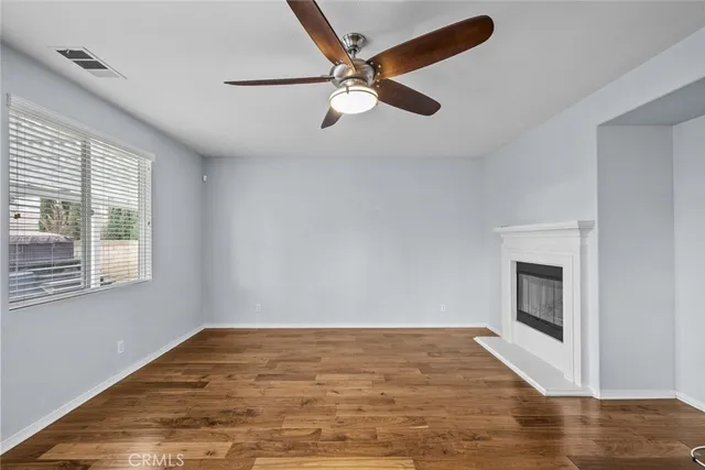 an empty room with wooden floor fan and windows