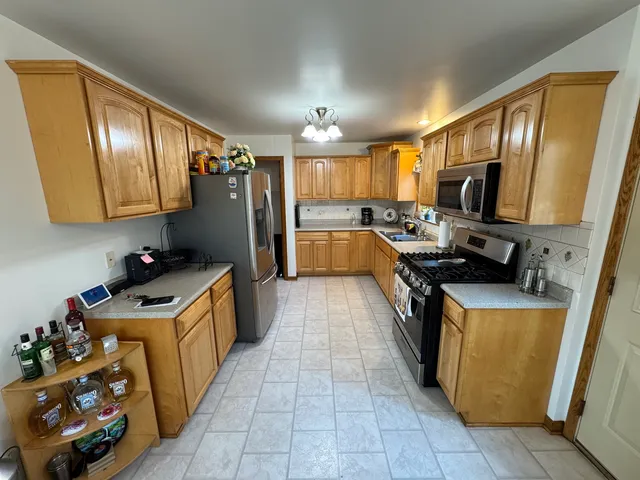 a kitchen with stainless steel appliances granite countertop a stove top oven a sink dishwasher and a refrigerator