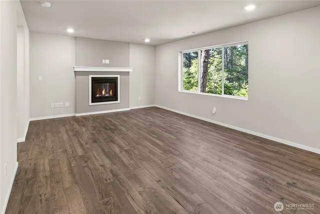 an empty room with wooden floor a fireplace and windows