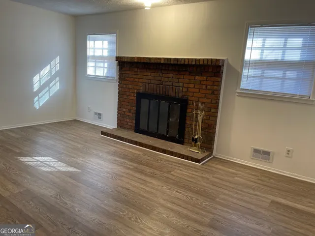 an empty room with wooden floor fireplace and windows