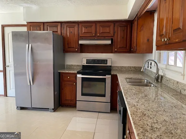 a kitchen with granite countertop a refrigerator stove and microwave