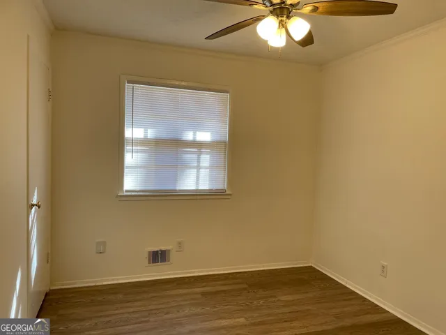 a view of empty room with wooden floor and fan