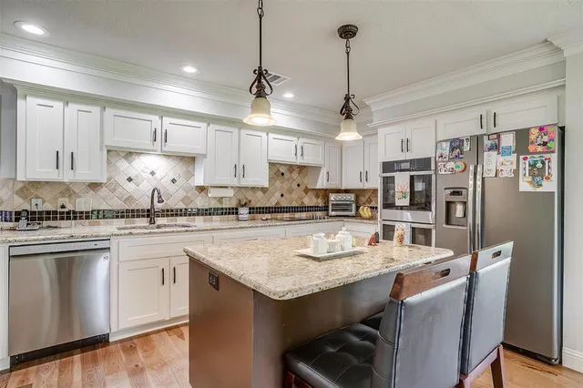a kitchen with stainless steel appliances granite countertop a sink a stove a refrigerator cabinets and chairs