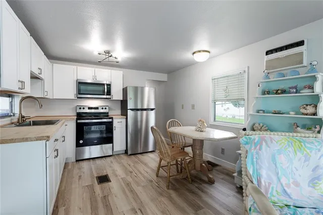a kitchen with stainless steel appliances a dining table chairs stove refrigerator and cabinets