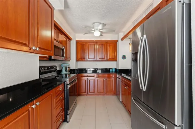 a large kitchen with stainless steel appliances granite countertop a refrigerator a sink dishwasher a stove and a microwave oven with cabinets