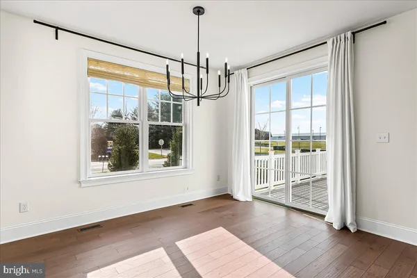 a view of an empty room with wooden floor and windows