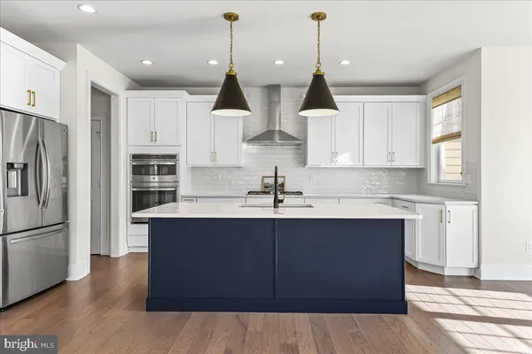 a kitchen with stainless steel appliances a sink a stove a refrigerator and white cabinets