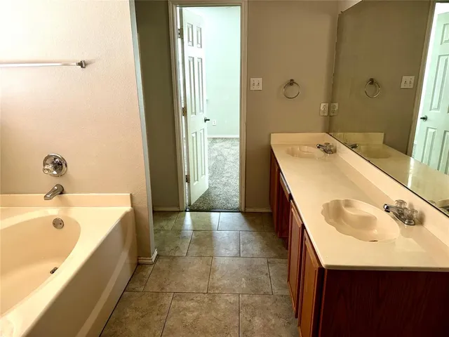 a spacious bathroom with a tub sink and mirror