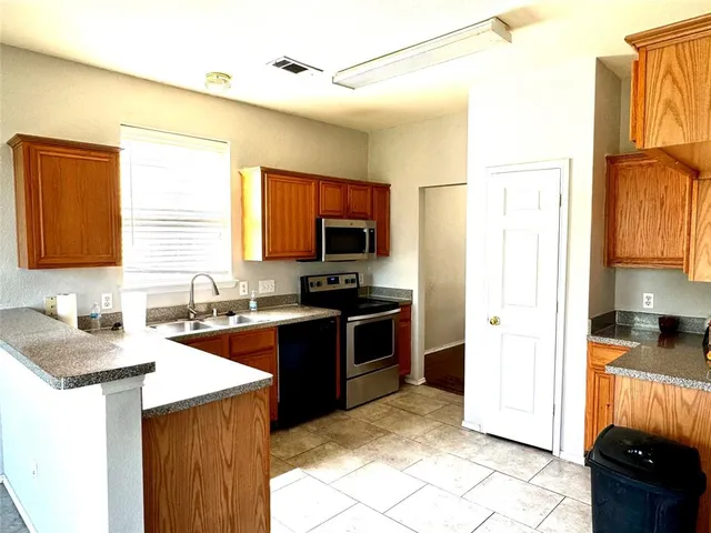 a kitchen with stainless steel appliances granite countertop a stove a sink a refrigerator and a microwave