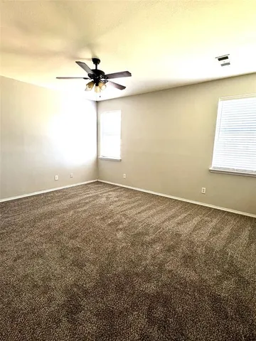 an empty room with windows and fan