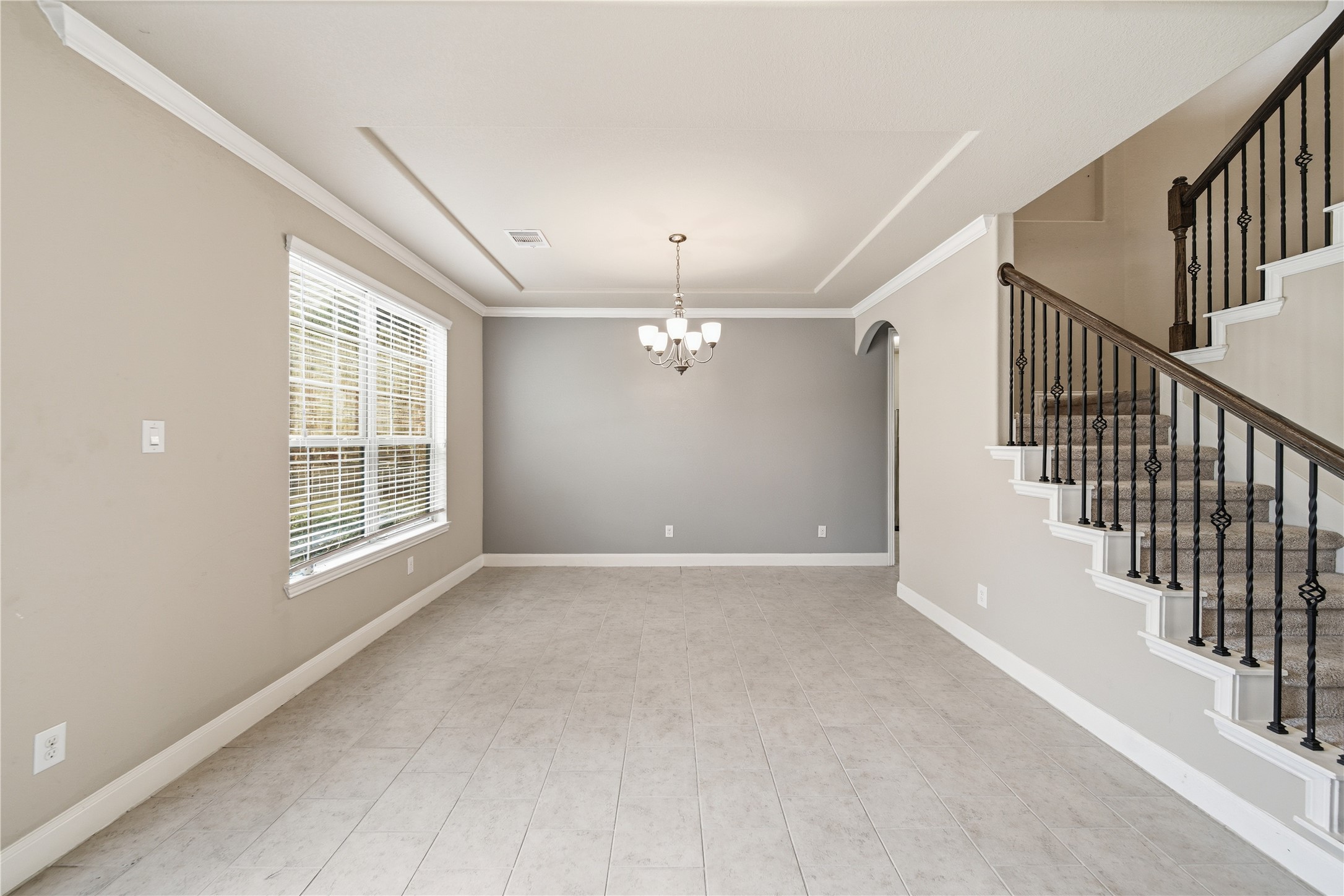 5303 Mesquite Willow Lane Rosharon, TX 77583 - Photo 3 of 32 Area features stylish accented walls, large windows for natural light, and a modern chandelier. It has tiled flooring and an elegant staircase with wrought iron railings, offering a versatile space.