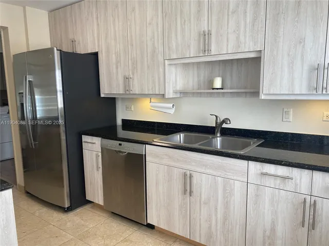 a kitchen with granite countertop a refrigerator sink and cabinets