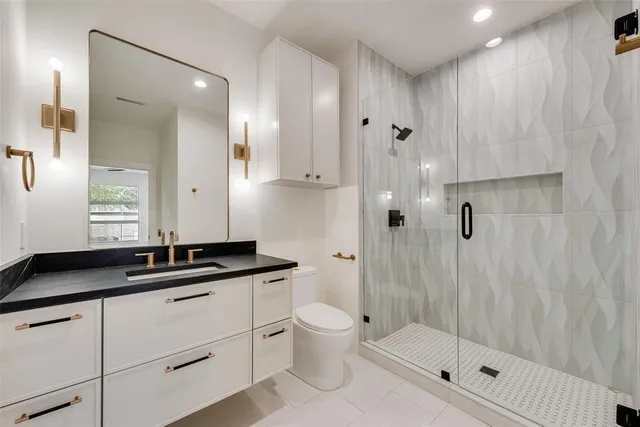 a bathroom with a granite countertop sink a toilet a mirror and shower
