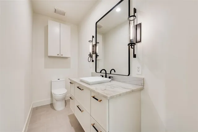 a bathroom with a granite countertop sink toilet and mirror