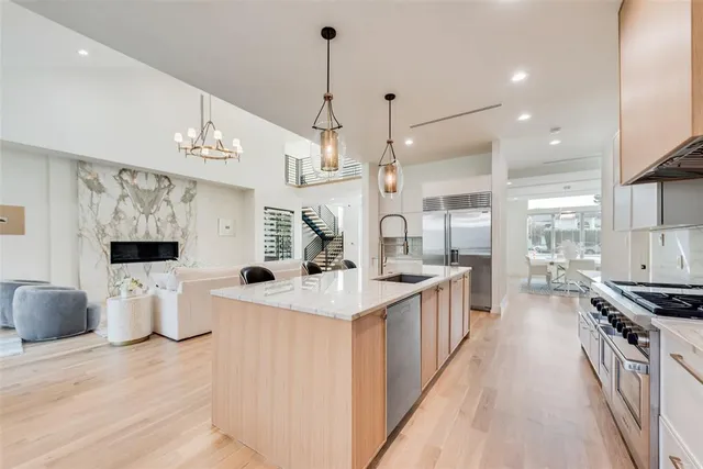 a open kitchen with stainless steel appliances granite countertop a sink a stove and a wooden floors