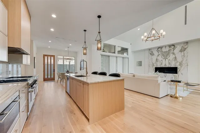 a large kitchen with stainless steel appliances kitchen island granite countertop a stove and a wooden floors