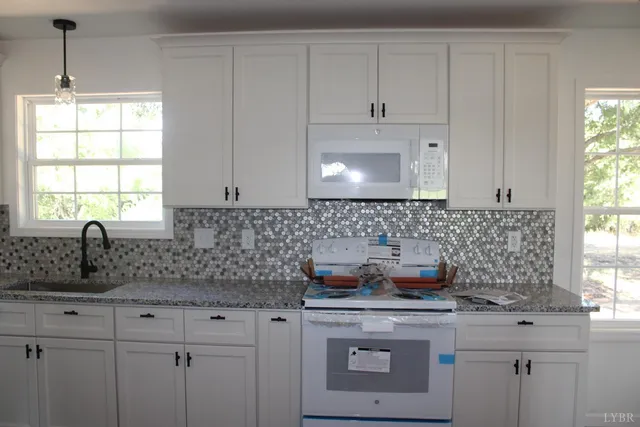 a kitchen with granite countertop a sink stove and cabinets