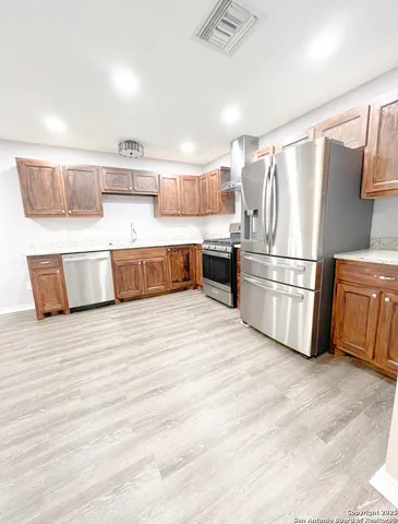a kitchen with stainless steel appliances a refrigerator and wooden floor