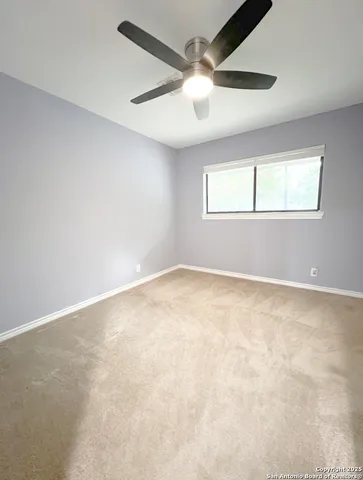 an empty room with a window and a fan