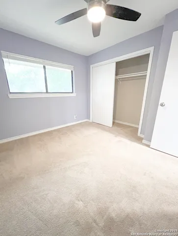 an empty room with a window and a ceiling fan