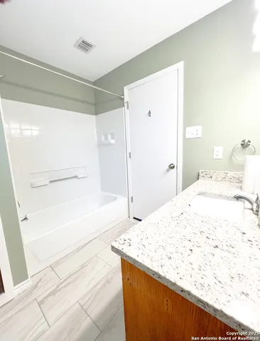 a bathroom with a granite countertop sink a bathtub and shower