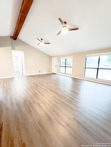 a view of an empty room with window and wooden floor