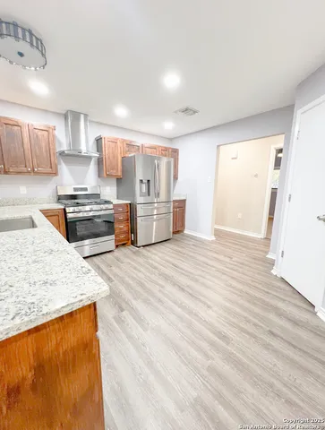 a large kitchen with kitchen island a stove a sink dishwasher and white cabinets with wooden floor