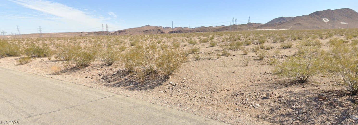 Unobstructed desert terrain opens up to sweeping mountain backdrops under vast blue skies.