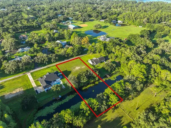 an aerial view of a residential houses with a yard and lake view