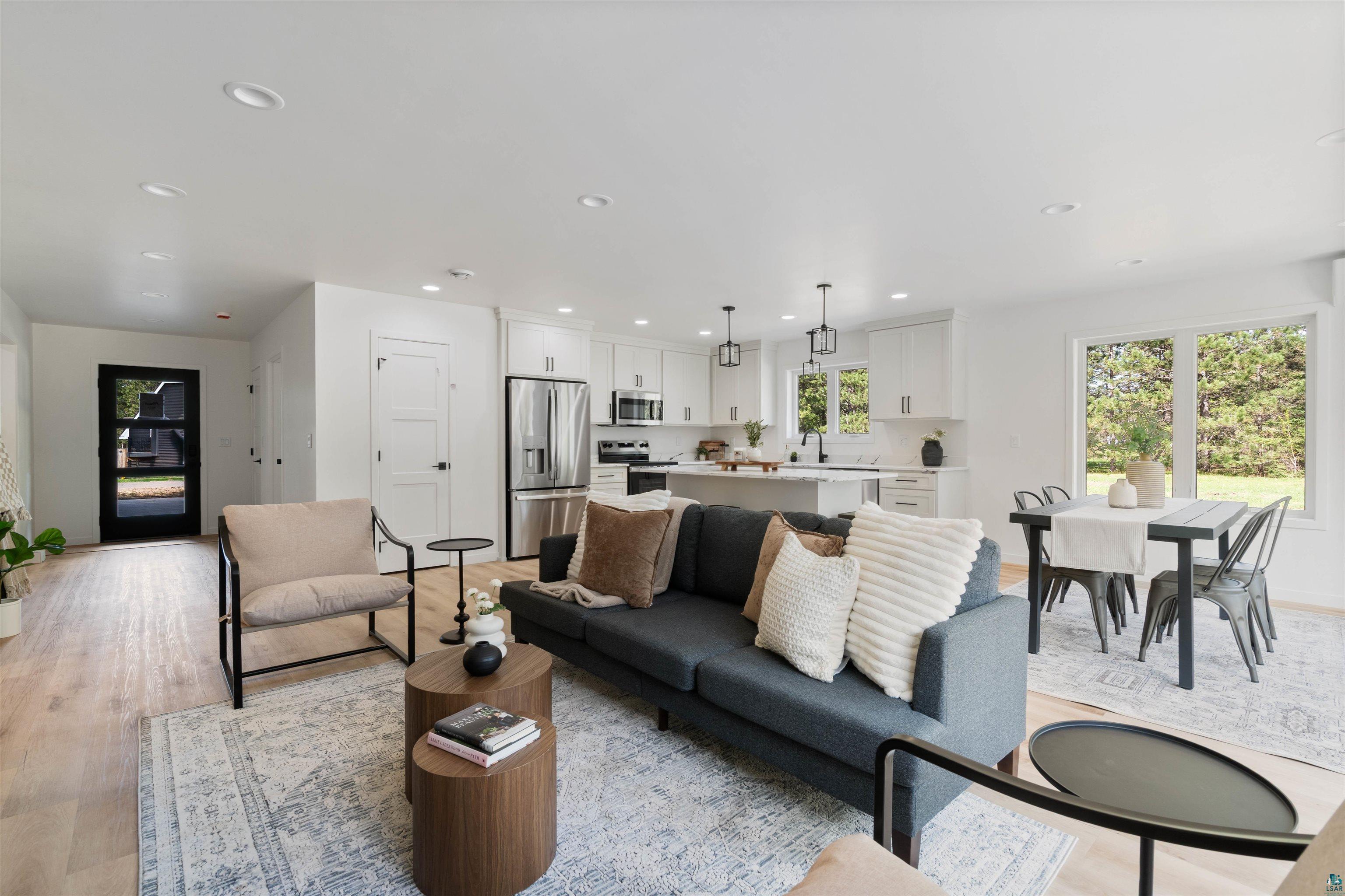 1386 Stephen Road Cloquet, MN 55720 - Photo 11 of 25 Open-concept living space featuring wood-finish flooring throughout, recessed ceiling lighting, a modern kitchen with stainless steel appliances, and a dining area with expansive window views