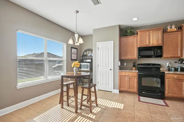 a open kitchen with stainless steel appliances granite countertop a stove top oven a refrigerator a sink and a chandelier