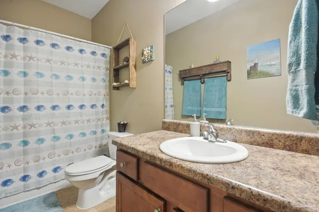 a bathroom with a granite countertop sink a toilet and a mirror