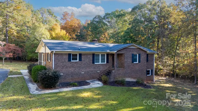 a view of a brick house with a yard potted plants and large tree