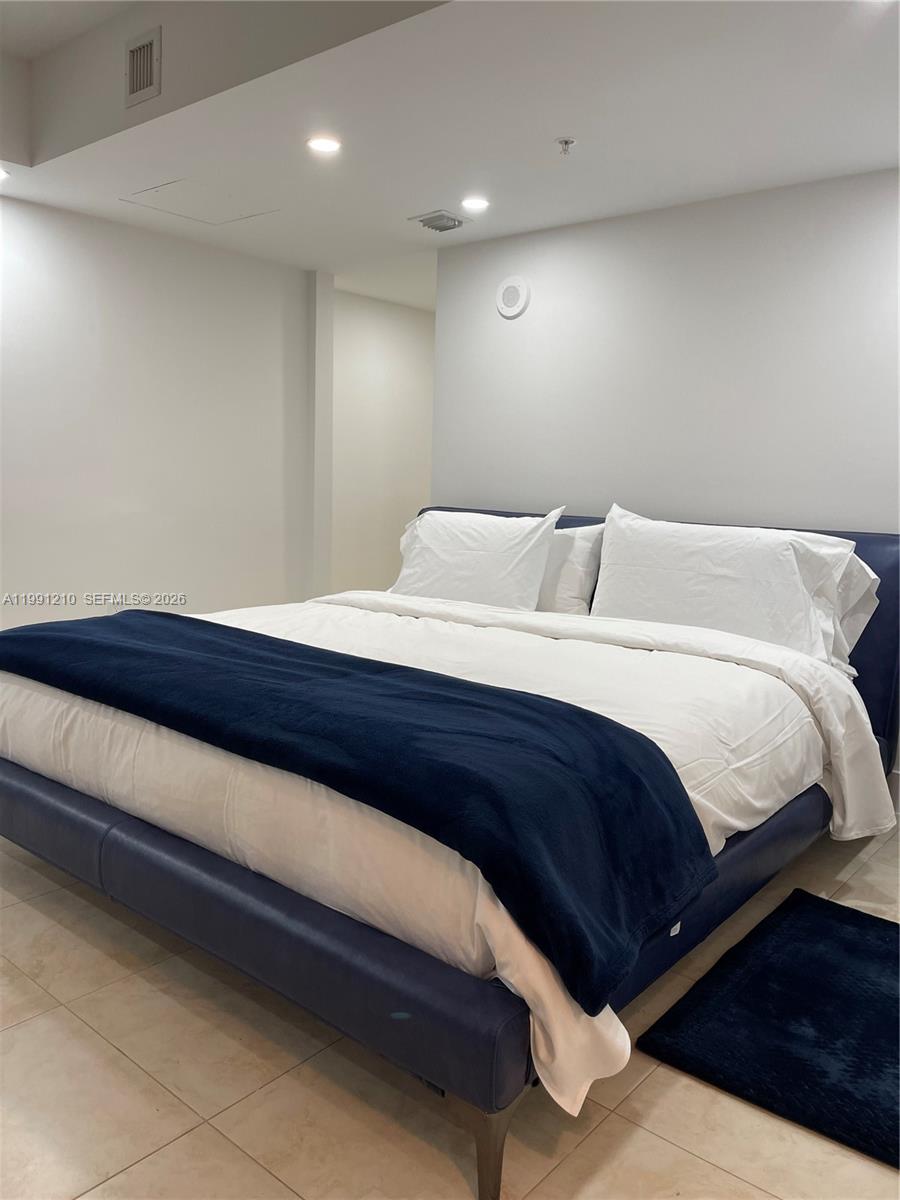 41 Southeast 5th Street, Unit 2305 Miami, FL 33131 - Photo 14 of 56 a spacious bedroom with a bed and a night stand
