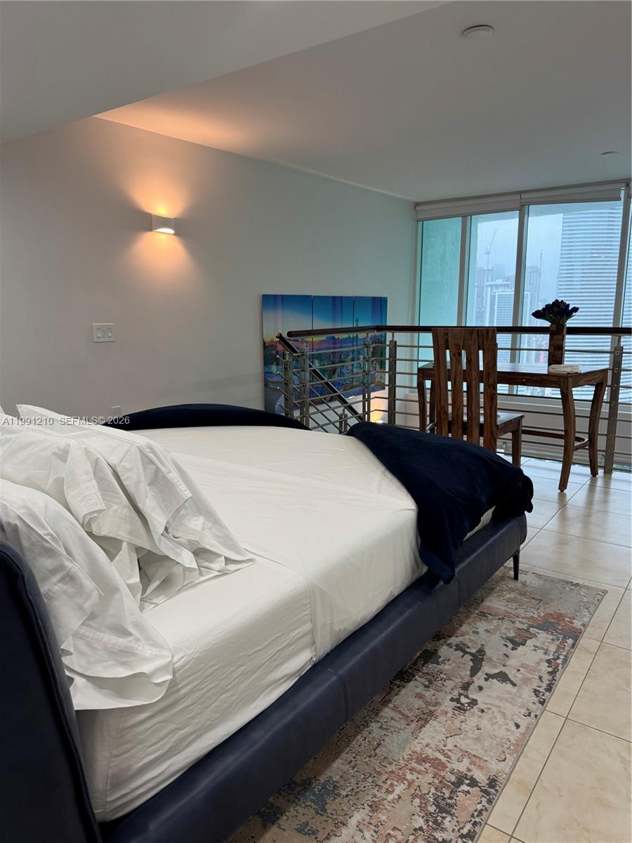 41 Southeast 5th Street, Unit 2305 Miami, FL 33131 - Photo 15 of 56 a bed sitting in a bedroom next to a lamp
