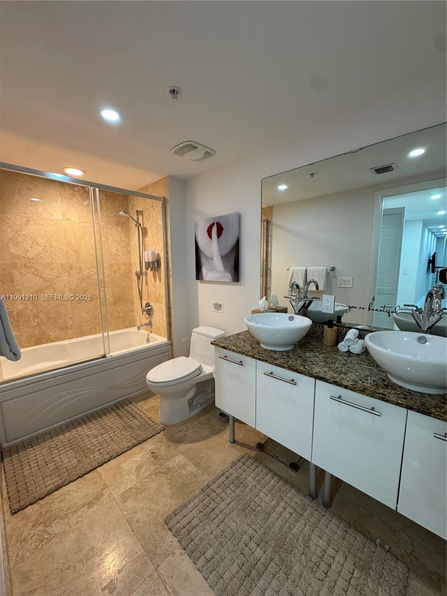 41 Southeast 5th Street, Unit 2305 Miami, FL 33131 - Photo 22 of 56 a large bathroom with a double vanity sink a toilet a mirror and a tub