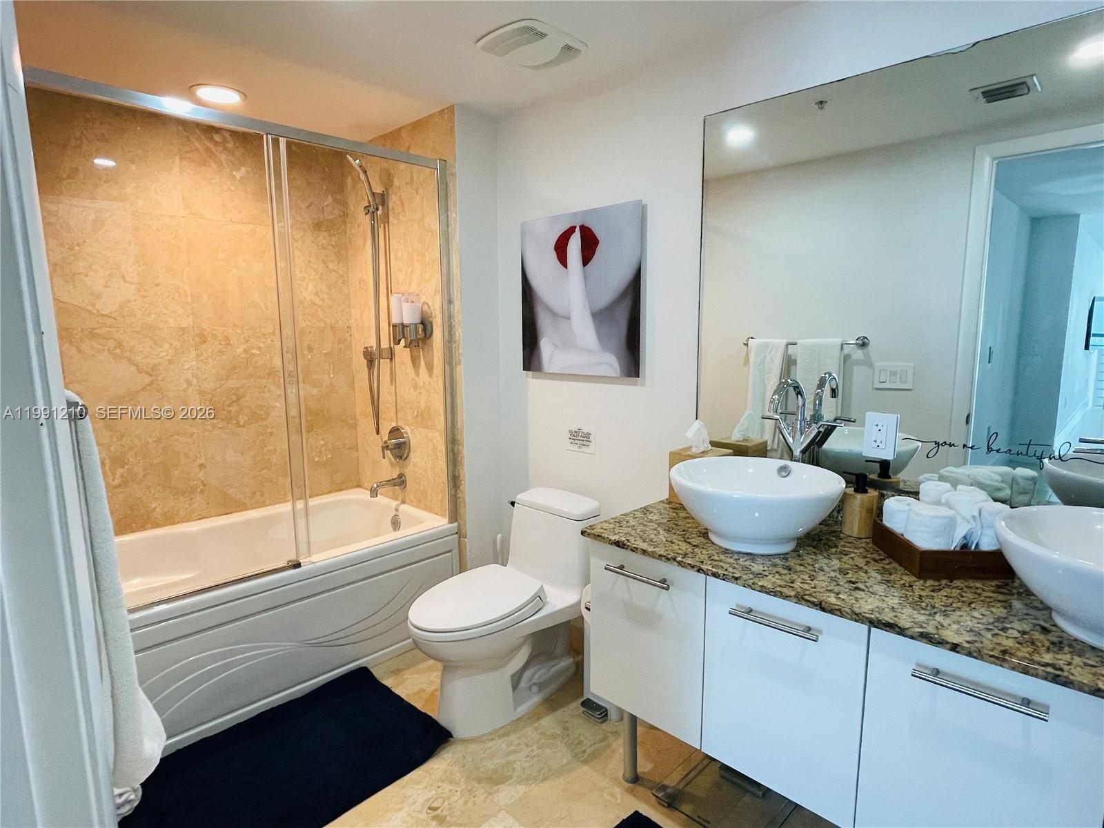 41 Southeast 5th Street, Unit 2305 Miami, FL 33131 - Photo 23 of 56 a spacious bathroom with a granite countertop sink toilet and shower