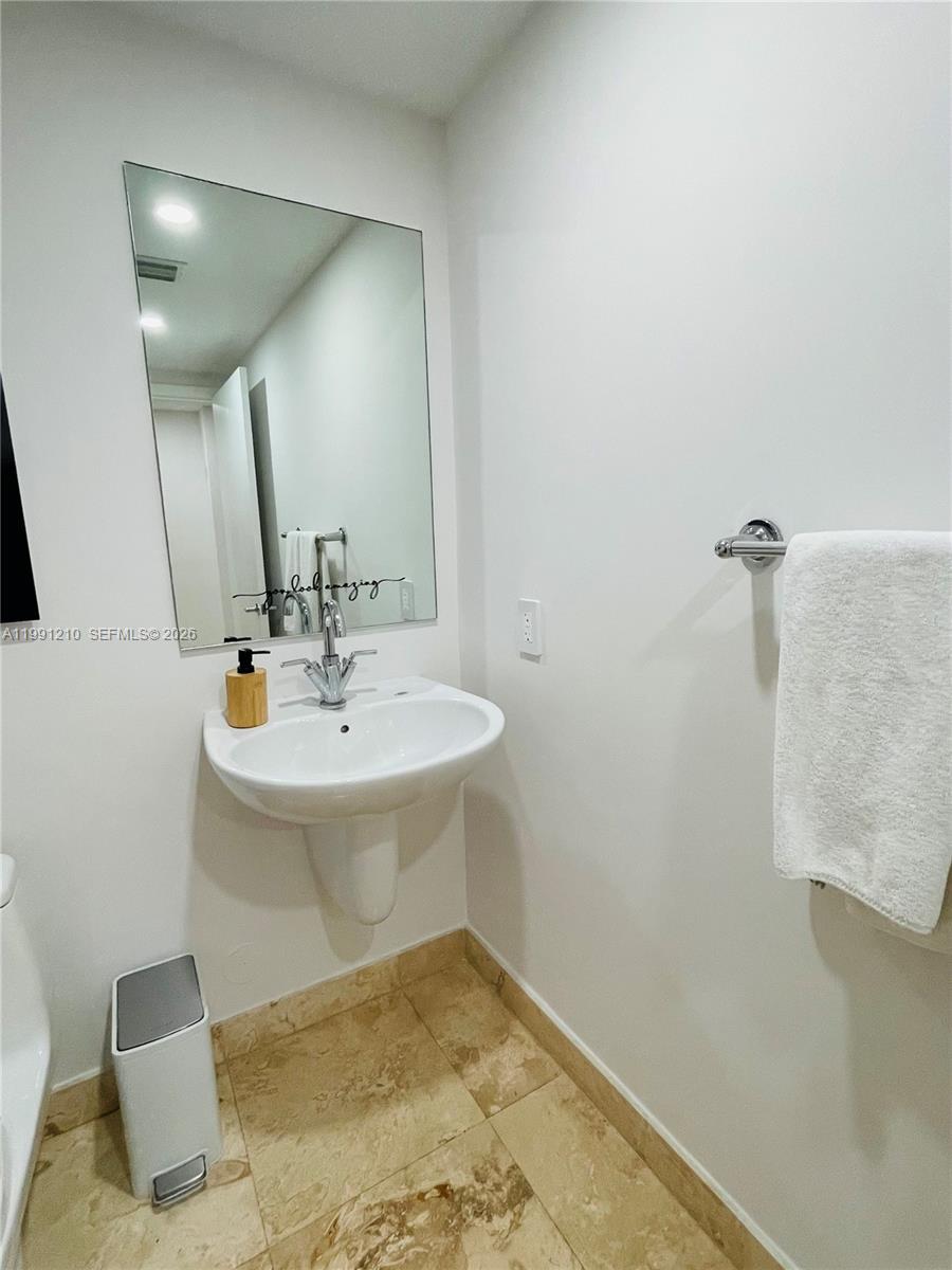 41 Southeast 5th Street, Unit 2305 Miami, FL 33131 - Photo 40 of 56 a bathroom with a sink a mirror and vanity