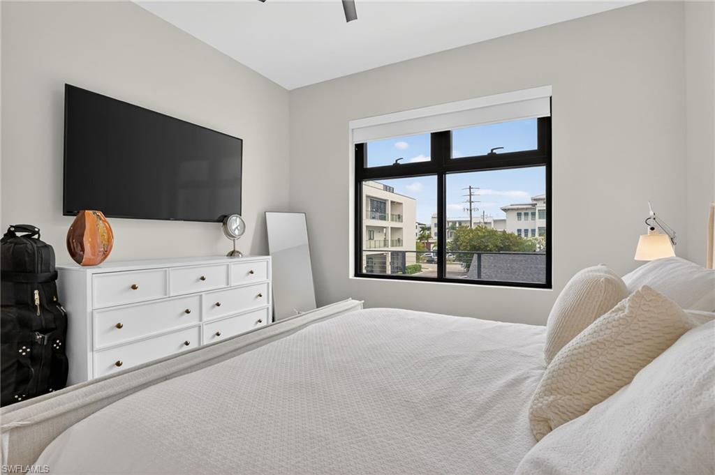 850 Central Avenue, Unit 208 Naples, FL 34102 - Photo 30 of 44 a bedroom with a bed and flat tv screen on the dresser