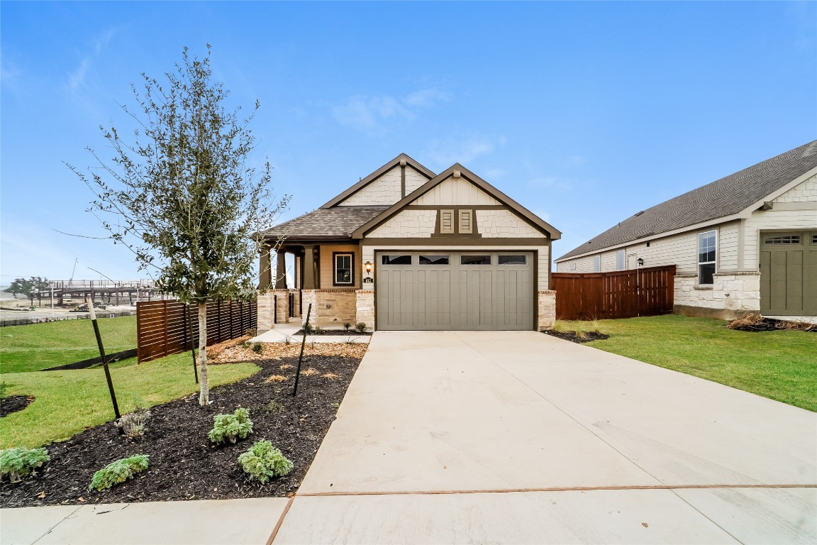 Craftsman inspired home featuring concrete driveway, an attached garage, and stone siding
